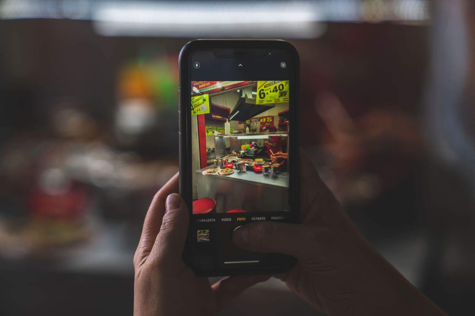 Main tenant un téléphone pour photographier une cuisine aménagée terminée