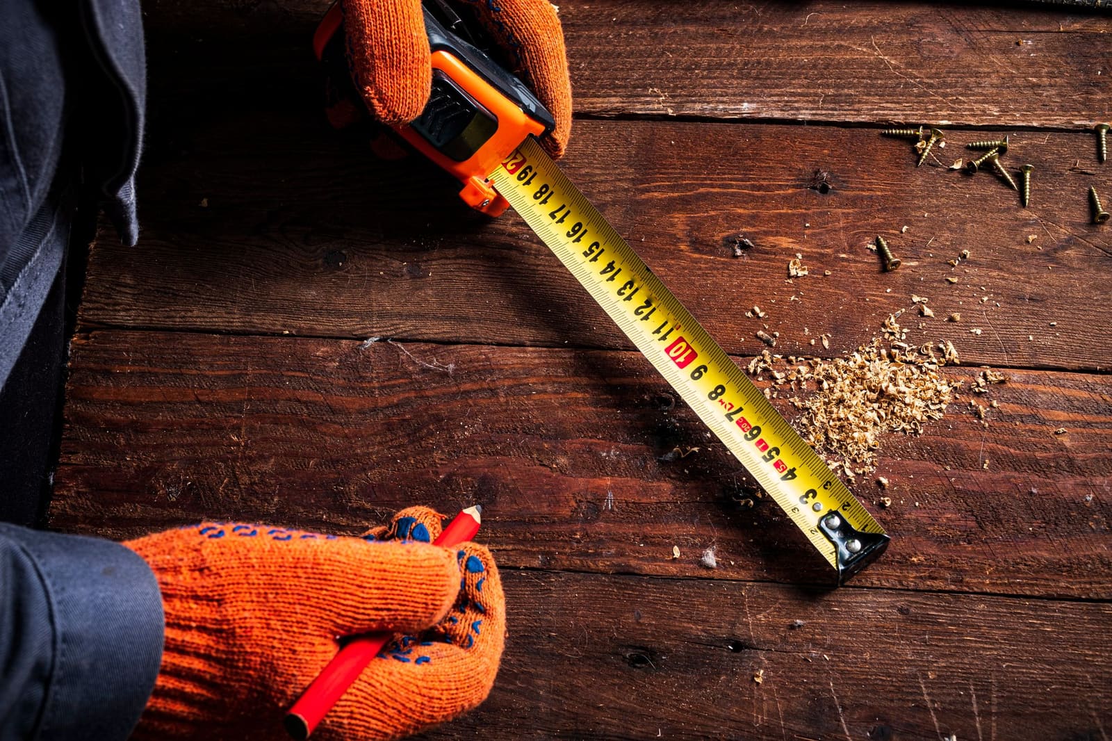 Menuisier prenant des mesures sur un escalier en bois en cours de pose