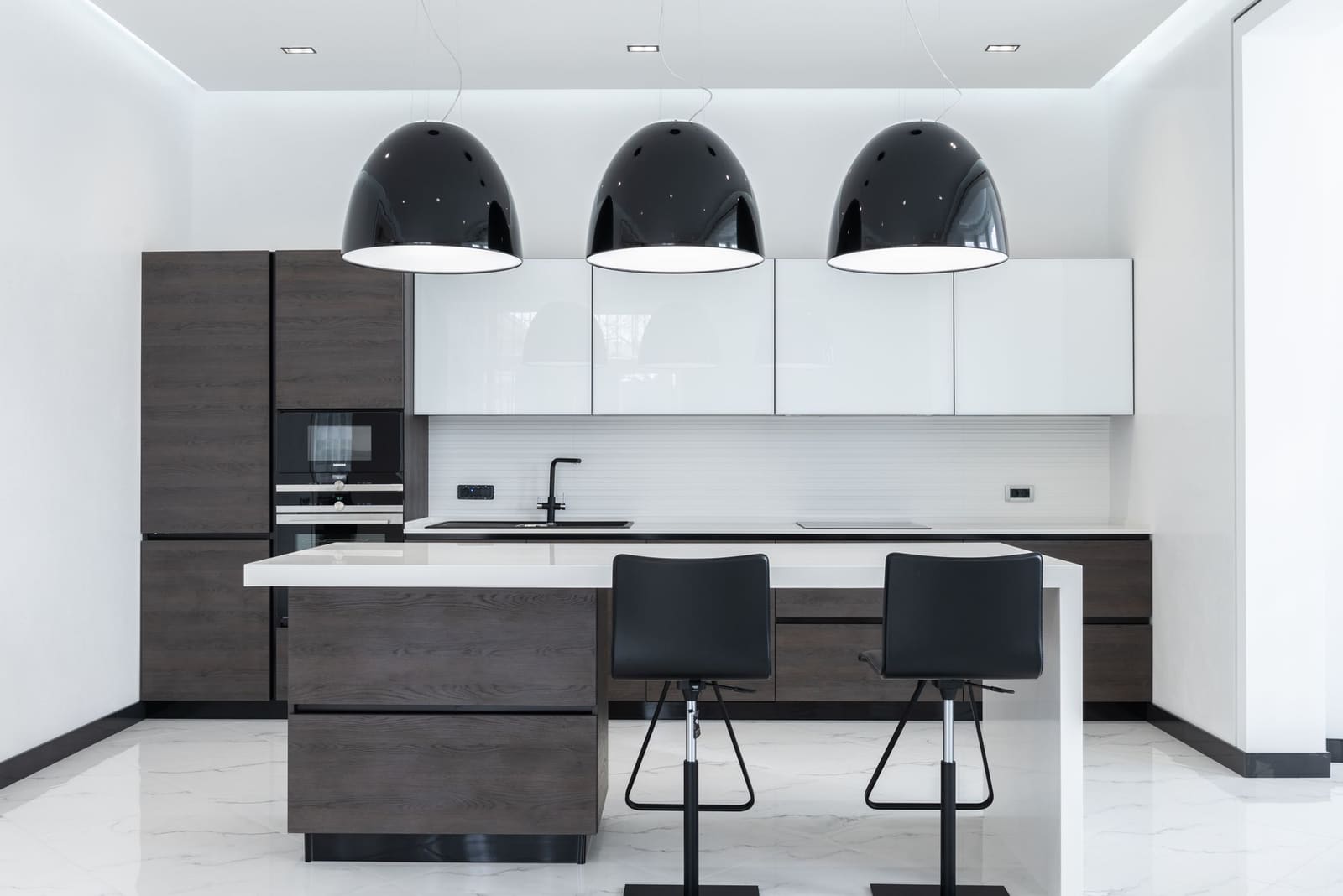 Showroom de cuisines avec meubles blancs et plan de travail en bois sous un éclairage doux